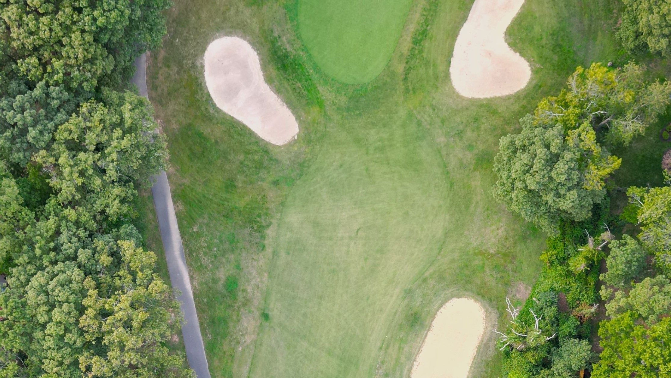 An aerial view of the golf course. 3 sand dunes surround the hole.